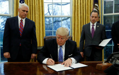 Ông Trump ký sắc lệnh hành pháp (executive order) dưới sự chứng kiến của Phó tổng thống - Mike Pence (trái) và Chánh Văn phòng Nhà Trắng - Reince Priebus tại Phòng Bầu dục ngày 23/1 (theo giờ Washington). Ảnh: Reuters.