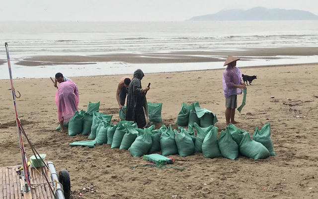 Xúc các bao tải cát để chặn lên mái nhà.
