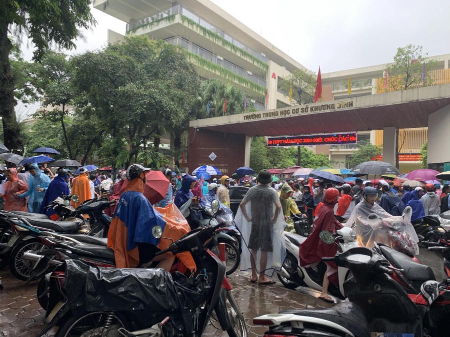 Phụ huynh đội mưa đưa đón con đi thi. (Ảnh: Phạm Duy)