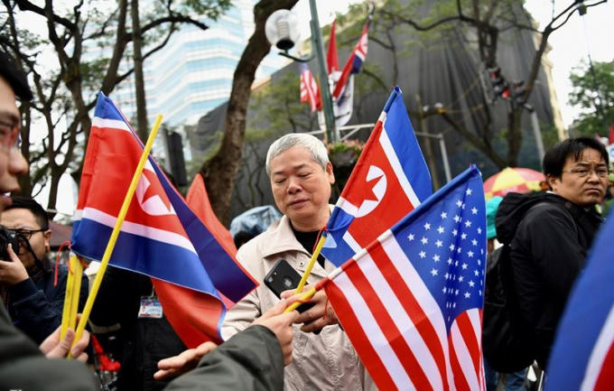 Người dân cầm cờ Triều Tiên và cờ Mỹ đứng trước khách sạn Melia.