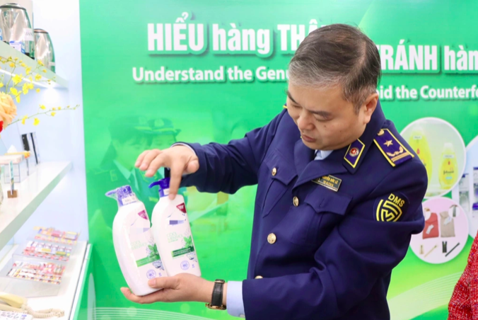 Ông Nguyễn Đức Lê, Phó Trưởng phòng Nghiệp vụ Quản lý thị trường hướng dẫn cách phân biệt 2 chai dầu gội thật và giả (Ảnh: Dms).