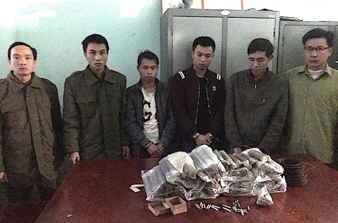 3 đối tượng (đứng giữa, bị còng tay) bị bắt về dùng thuốc nổ trái phép để khai thác vàng (Ảnh: V.H)