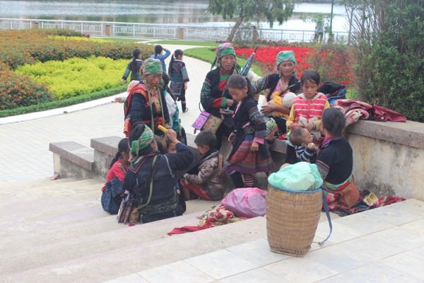 Từng tốp phụ nữ và em nhỏ dừng chân nghỉ ngơi và chuyện trò sau buổi đi chợ.