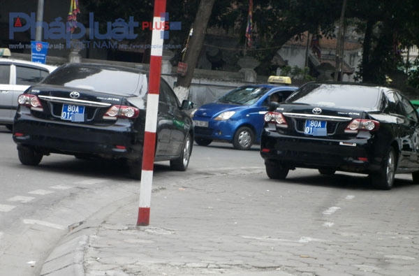 Hai chiếc xe biển xanh nằm chình ình dười lòng đường trước cổng đền Quán Thánh. Ảnh: Như Trường.