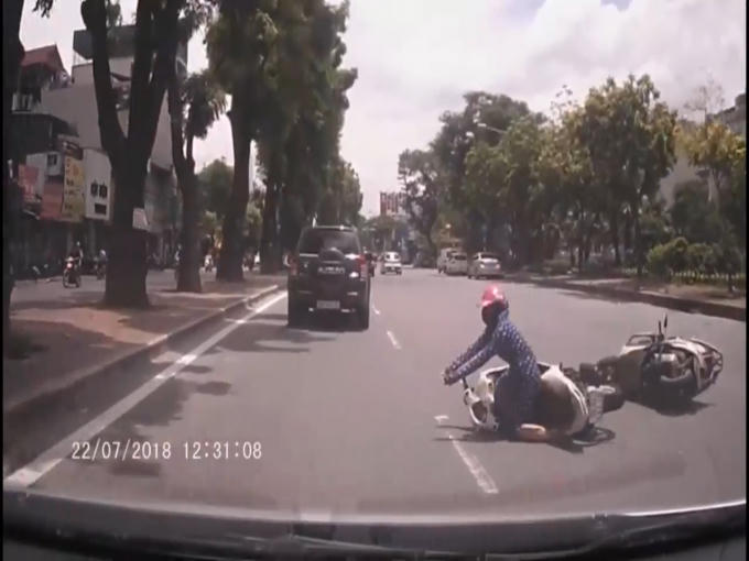 Một người phụ nữ đã ngã ngay đầu chiếc ô tô đi cùng chiều. (Ảnh: Cắt từ clip)