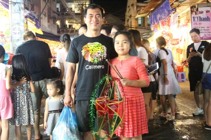 Bé gái này được bố mua cho hai chiếc lồng đèn hình ngôi sao. Trước khi ra về, hai bố con cũng nhờ phóng viên chụp dùm tấm hình để làm kỉ niệm.