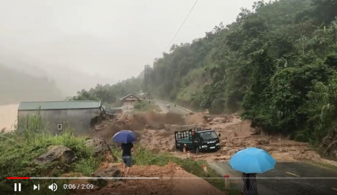 Một ngôi nhà ven đường và chiếc ô tô đang lưu thông súy bị cuốn trôi. (Ảnh cắt từ clip)