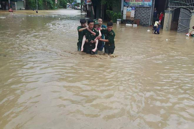 Các chiến sỹ biên phòng cõng người dân ra khỏi nơi ngập lụt. (Ảnh: Hải Thượng).