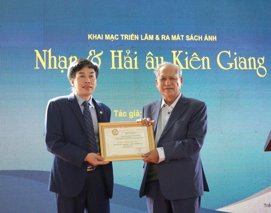 Ông Hồ Sĩ Minh, Phó Chủ tịch Hội Nghệ sĩ nhiếp ảnh Việt Nam trao Quyết định bảo trợ triển lãm ảnh nghệ thuật cá nhân Nhạn và Hải âu cho Nghệ sĩ nhiếp ảnh Trần Lam