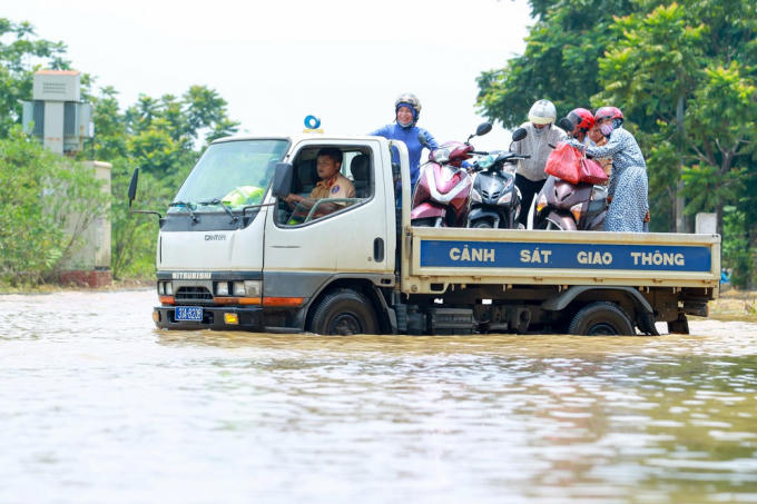 Người và xe người dân được vận chuyển qua đoạn ngập sâu.