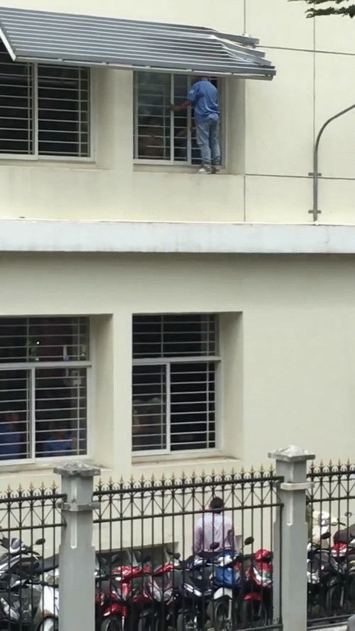 Nam sinh đứng cố thủ ở bậu cửa tầng 2, toan nhảy xuống - Ảnh cắt từ clip.