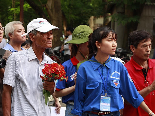 Ông Tạ Minh Đức (Hà Đông) cầm bó hoa nhỏ và hướng đôi mắt về phía cổng trường chờ cháu gái để tặng bó hoa nhỏ.