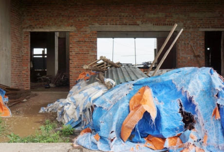 Bên trong tầng 1 căn nhà 9 tầng có nhiều đồ đạc, vật liệu xây dựng phủ bạt, "đắp chiếu".