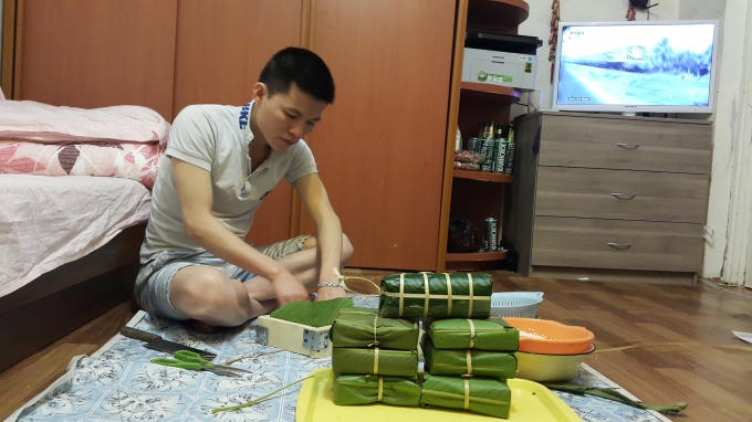Anh Tuấn tranh thủ gói bánh chưng trước khi đi làm. Ảnh: Tiến Hào.