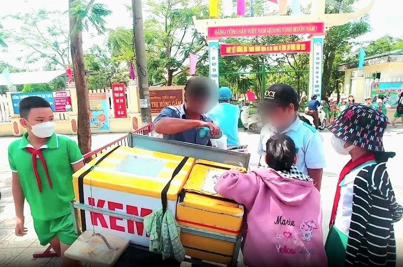 Thức ăn đường phố bày bán trước cổng trường thu hút nhiều học sinh, tiềm ẩn nguy cơ mất ATVSTP. Ảnh: Hoàng Bin