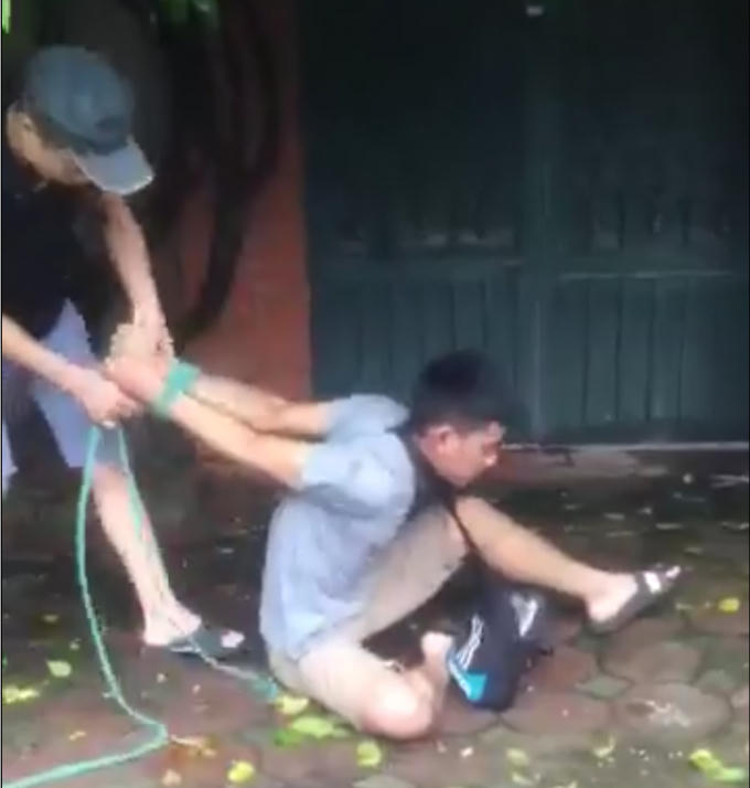 Nam thanh niên bị trói tay ngược ra đằng sau (ảnh cắt từ clip).