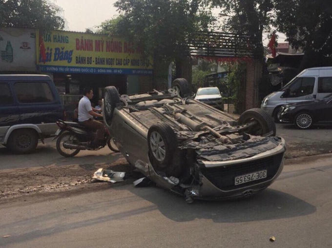 Sau khi gây tai nạn, chiếc xe ôtô màu ghi bị lật ngửa giữa đường.