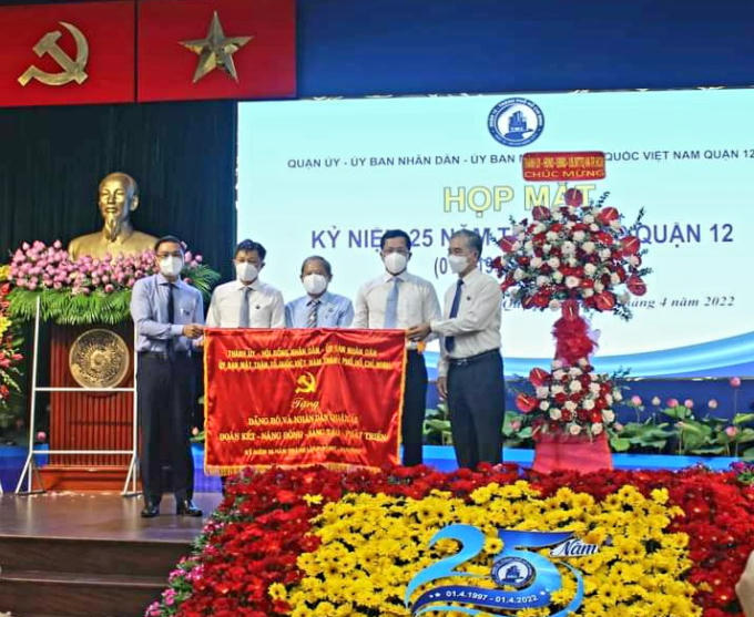 Phó chủ tịch UBND TP.HCM - Ngô Minh Châu (ngoài cùng bên phải) trao cờ của Thành ủy - HĐND - UBND - Ủy ban MTTQ Việt Nam TP.HCM cho lãnh đạo Q.12. Ảnh: Đình Chiến