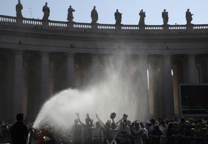 Lính cứu hỏa phun nước giúp đám đông chờ Giáo hoàng Francis "hạ hỏa" tại Quảng trưởng St Peter. Ảnh: Alessandra Trantino/AP