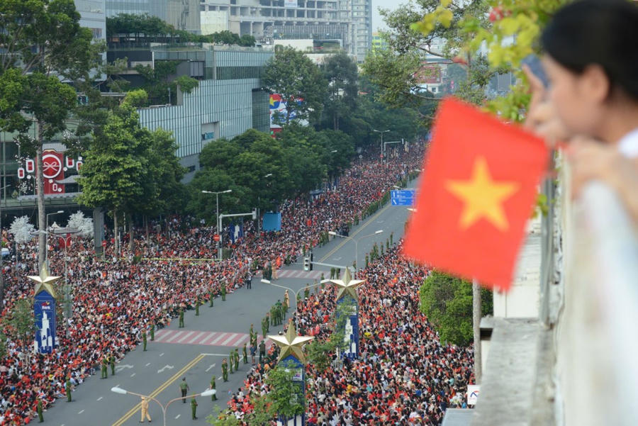 Nhiều người mang theo cờ Tổ quốc, mặc áo đỏ sao vàng, cổ vũ cho các lực lượng vũ trang sắp duyệt binh.