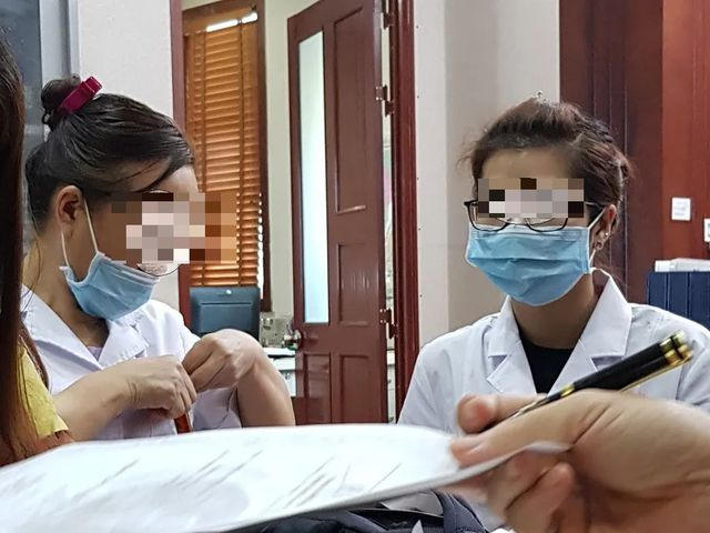 Chiếc khẩu trang luôn che trên mặt bác sĩ (bên phải) cùng nữ phiên dịch