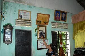 Nữ du kích Nguyễn Thị Thu bên những bằng khen, huy chương và bức ảnh kỷ niệm.