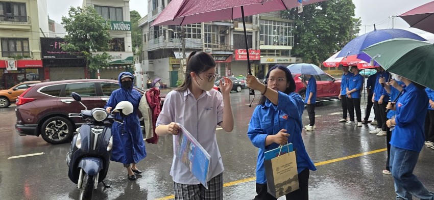 Tình nguyện viên đã chuẩn bị sẵn ô dù, che cho thí sinh để tránh bị ướt. Ảnh: Nguyễn Quang.