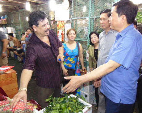 Bí thư Thành ủy TP.HCM (bìa phải) hỏi một tiểu thương chợ đầu mối Thủ Đức nguồn gốc trái cây. Ảnh: LÂM NGỌC