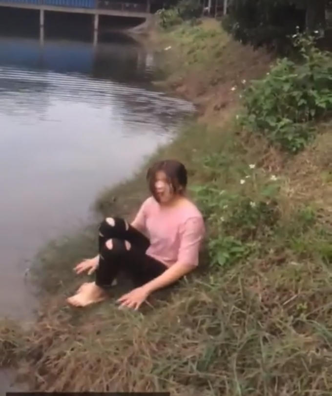 Cô gái ngồi trên bờ run rẩy sau khi ngoi lên bờ - Ảnh cắt từ clip.