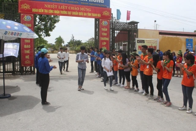Nhóm sinh viên tình nguyện chào đón những thí sinh bước ra khỏi phong thi đầu tiên. (Ảnh chụp tại điểm thi trường Hàm Rồng, TP Thanh Hóa).