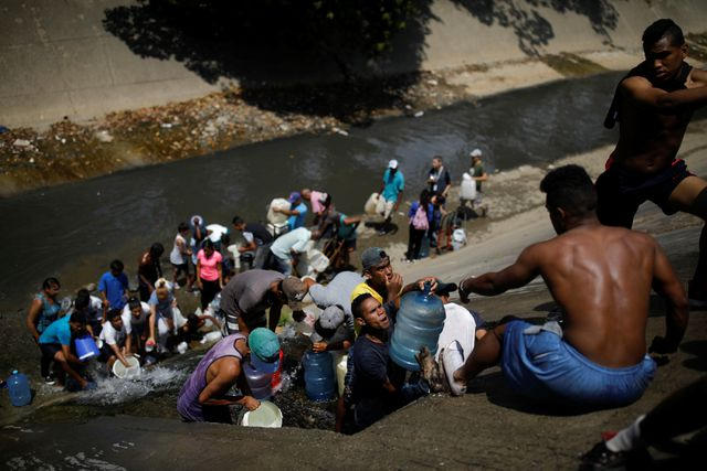 Người dân Venezuela buộc phải lấy nước từ đường ống thoát nước để đảm bảo sinh hoạt trong những ngày thiếu điện. (Ảnh: Reuters)