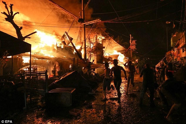 Người dân bỏ chạy sau khi đám cháy lan sang khu vực dân cư ở Manila. (Ảnh: EPA)