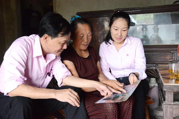 Các cán bộ NHCSXH nghe cựu TNXP Trương Thị Oanh kể về những ngày mở đường cho xe ra tiền tuyến.