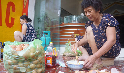 Bà Thìn (bên phải) đang nấu thức ăn bên chiếc bếp dã chiến trên vỉa hè. Ảnh: Lê Hoàng.