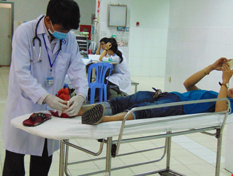 BS Lê Minh Đông khám vết thương chân cho một ông bị kiếng cắt. Ảnh: TRẦN NGỌC