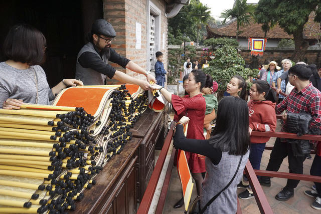 Người dân đủ mọi lứa tuổi phải xếp hàng mua giấy đỏ trước khi tới gặp các ông đồ "xin chữ".