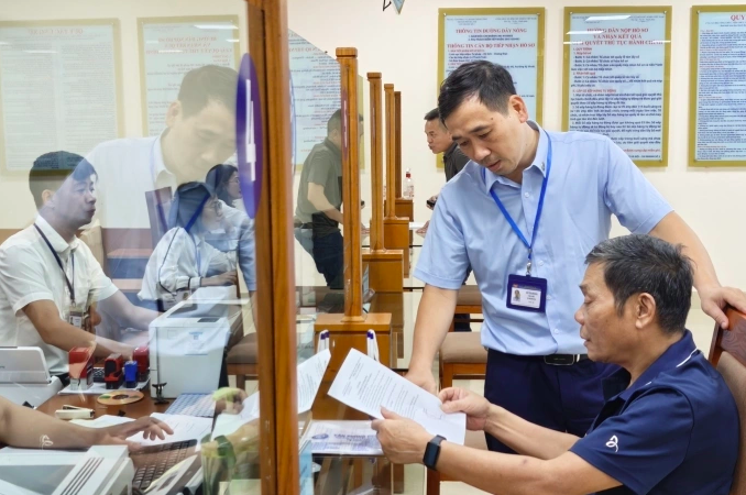 Công chức Trung tâm Phục vụ hành chính công thành phố Hà Nội chi nhánh số 3 hướng dẫn người dân sử dụng dịch vụ công. Ảnh: Trọng Đạt