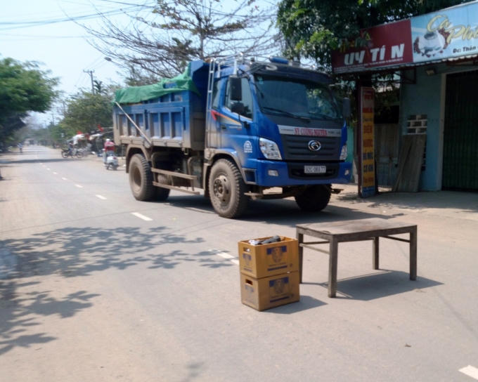 Người dân dùng bàn ghế, thùng bia để chặn đoàn xe tải chở đất.