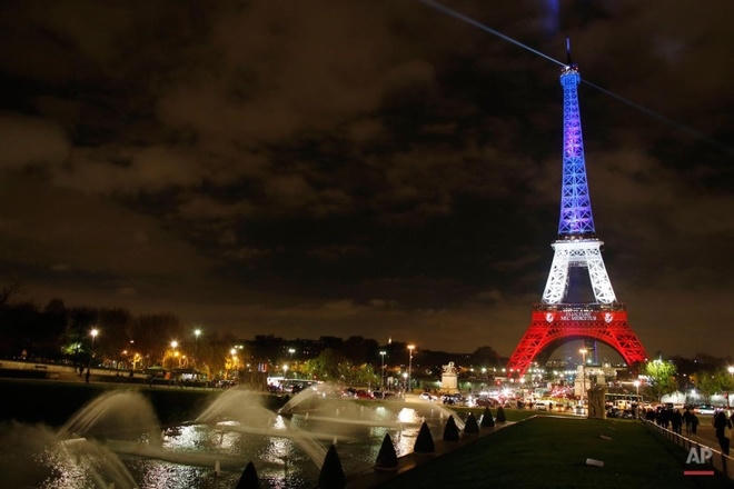 Tháp Eiffel ở Paris tỏa ánh sáng theo ba màu trên quốc kỳ Pháp hôm 16/11, sau vụ khủng bố vào các nhà hàng, nhà hát và sân vận động thủ đô làm 130 người chết. Đây là vụ tấn công đẫm máu nhất vào Paris kể từ Thế chiến II. Ảnh: AP.