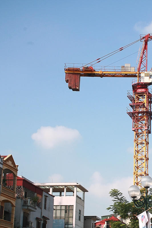 Một chiếc cẩu tháp có khối bê tông đối trọng nằm lơ lửng trên đầu nhà dân