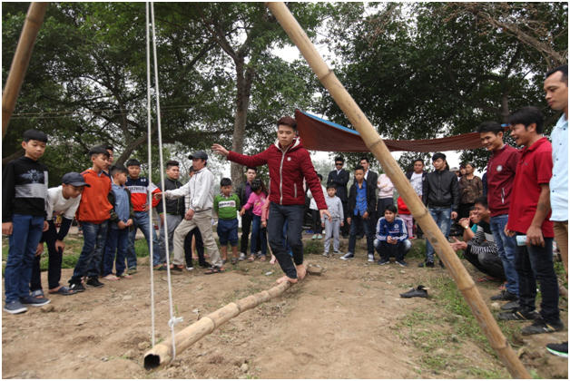 Các bạn thanh niên tham gia trò chơi đi thăng bằng trên cây tre.