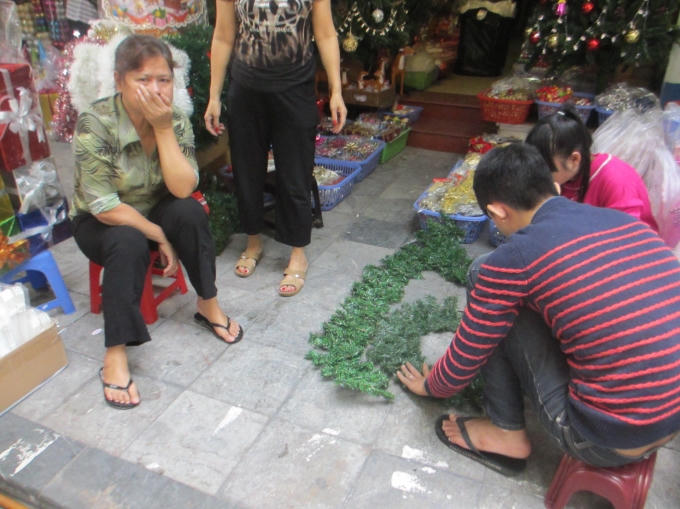 Người đàn ông cùng mọi người đang làm cây thông Noen chuẩn bị cho mùa lễ Giáng sinh sắp tới