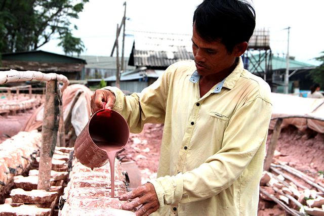 Thợ thủ c&ocirc;ng đổ đất s&eacute;t v&agrave;o khu&ocirc;n để tạo h&igrave;nh.