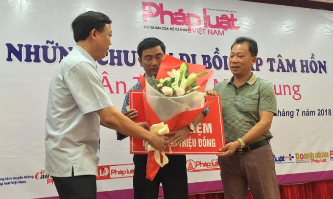 Tiến sĩ Đào Văn Hội, Tổng Biên tập Báo PLVN (bên phải), cùng lãnh đạo địa phương trao quà cho một bạn đọc khó khăn tại miền Trung tháng 7/2018.