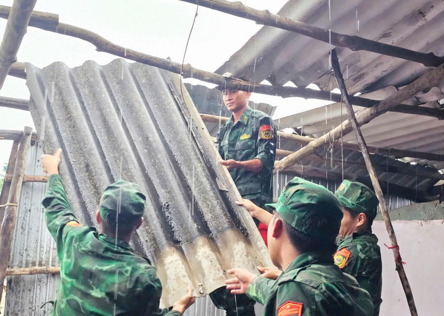Cán bộ, chiến sĩ Đồn Biên phòng Đất Mũi hỗ trợ hộ bà Cao Thị Nữ khắc phục hậu quả thiên tai gây ra.