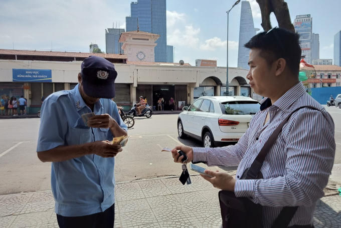 Ông Phạm Văn Minh tạm thu phí đậu xe bằng tiền mặt cho khách.