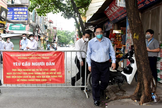 Thủ tướng Phạm Minh Chính cùng Bộ trưởng Bộ Y tế và lãnh đạo TP Hà Nội kiểm tra điểm nóng dịch COVID-19 tại quận Thanh Xuân. (Ảnh: Báo Công an Nhân dân)