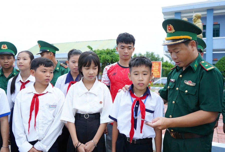 Thiếu tá Phạm Nam Sơn - Chính trị viên Đồn Biên phòng Đất Mũi tặng BHYT cho học sinh nghèo.