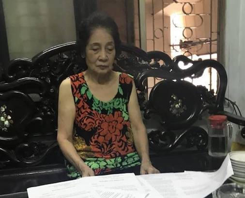 Bà Đặng Thị Gái mệt mỏi bên đống hồ sơ giấy tờ liên quan đến việc cấp sổ đỏ nhà mình.