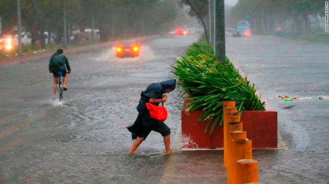 Một vài người đi trong cơn mưa lớn và gió mạnh ở Manila.